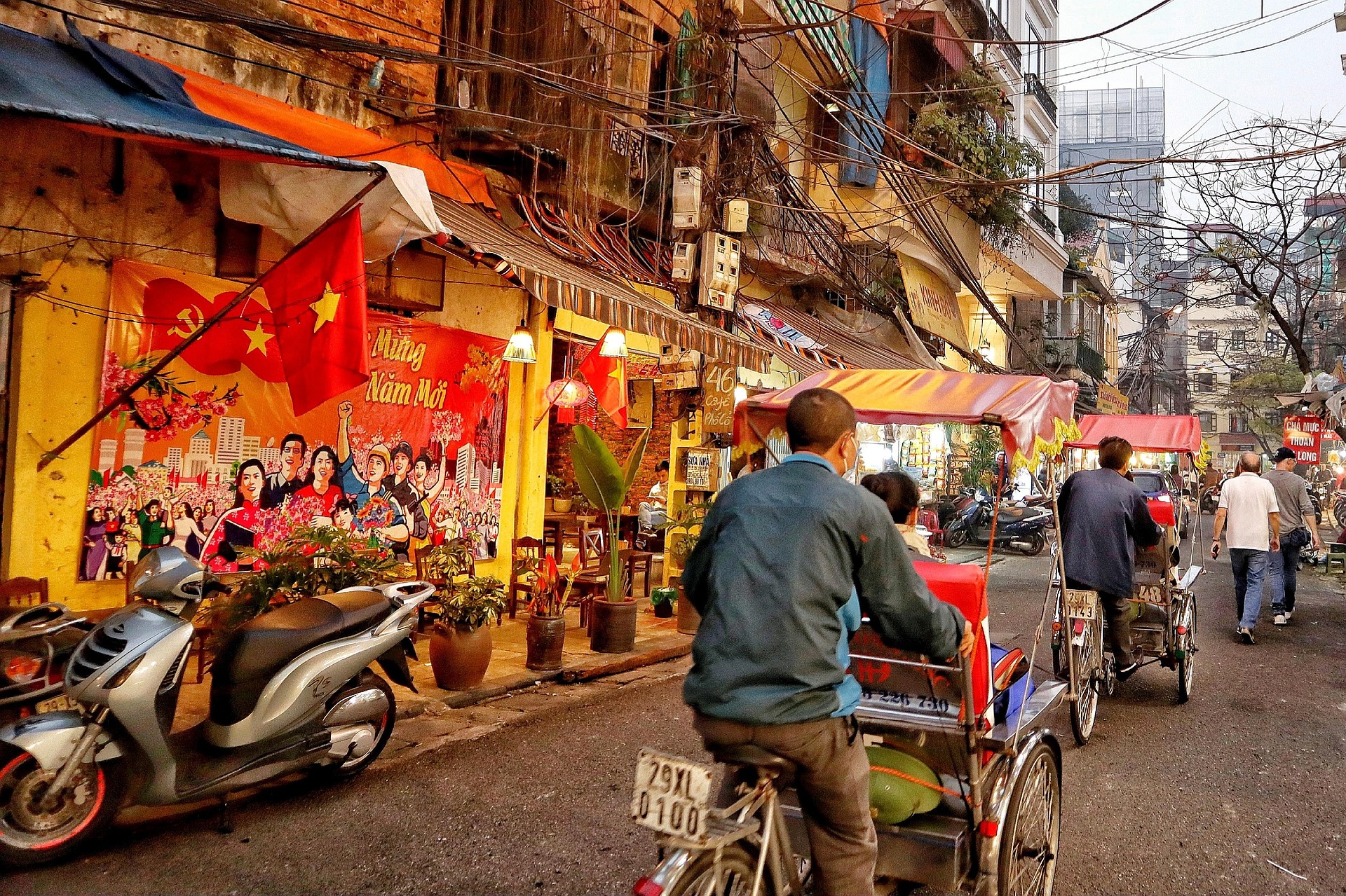 a street scene in Hanoi, rikshas passing stores,